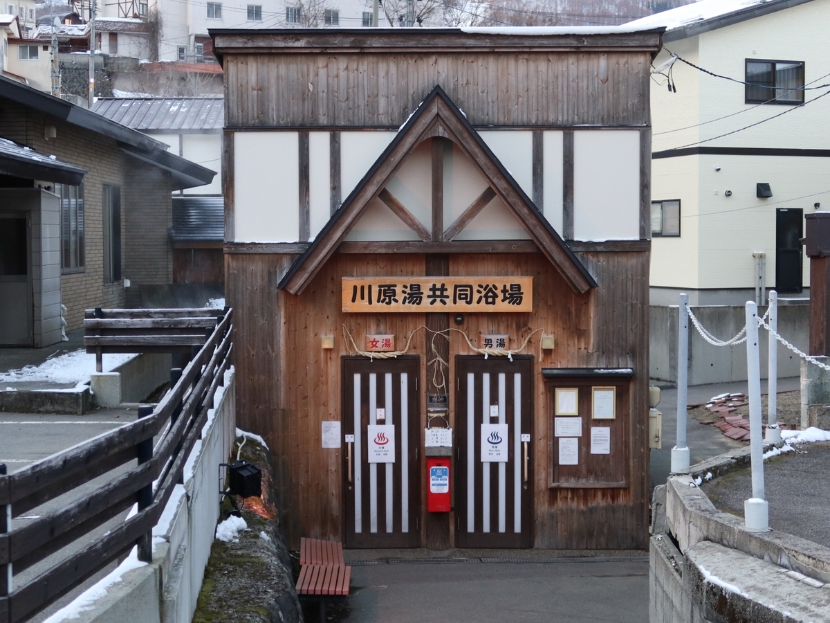 雪の残る温泉街に建つ木造の共同浴場