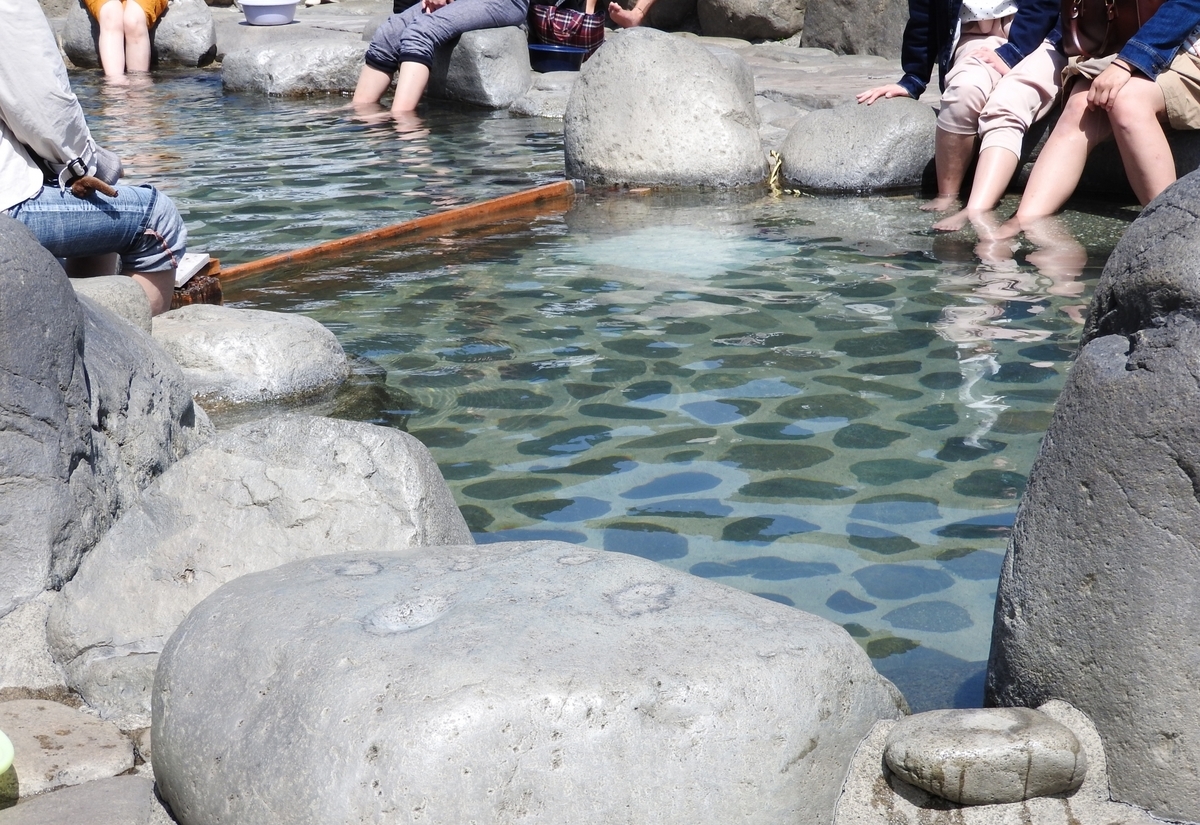 岩に囲まれた透明な湯の足湯