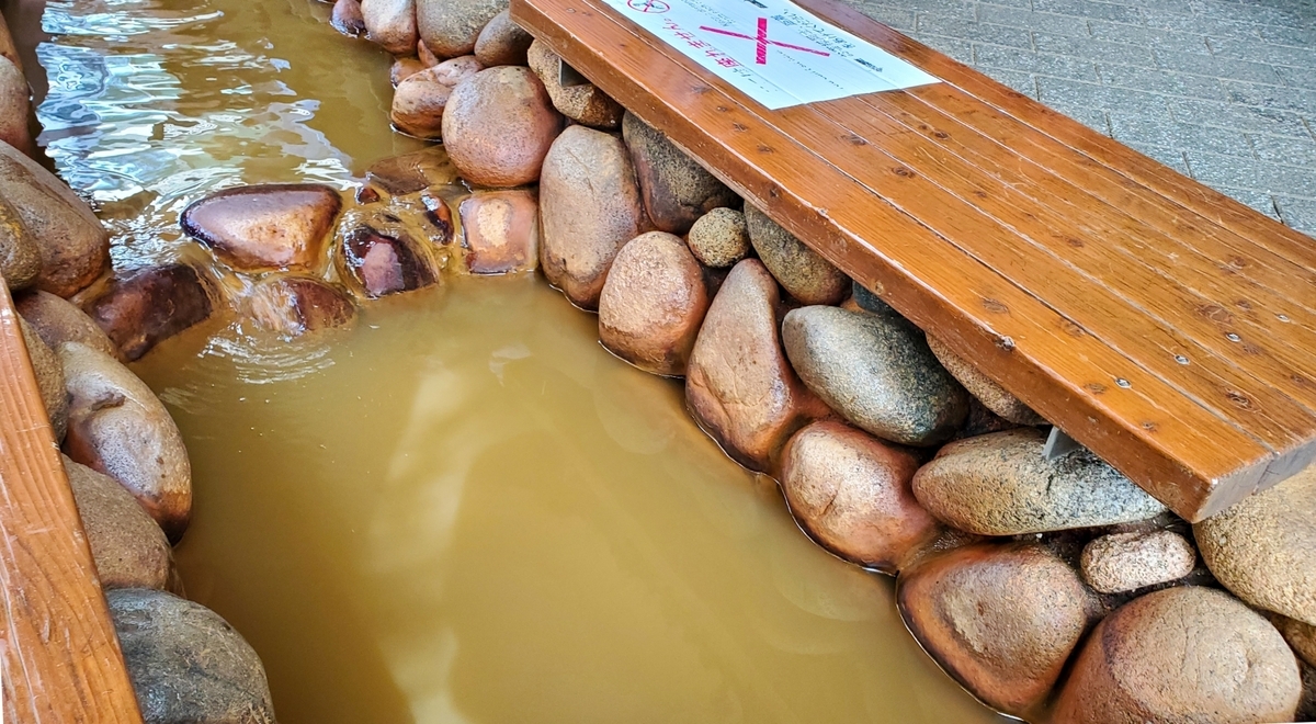 石組みの足湯に満ちる黄金色の温泉
