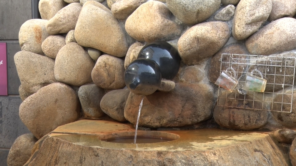 石壁の湯口から飲泉用の湯が流れるひしゃく置き場