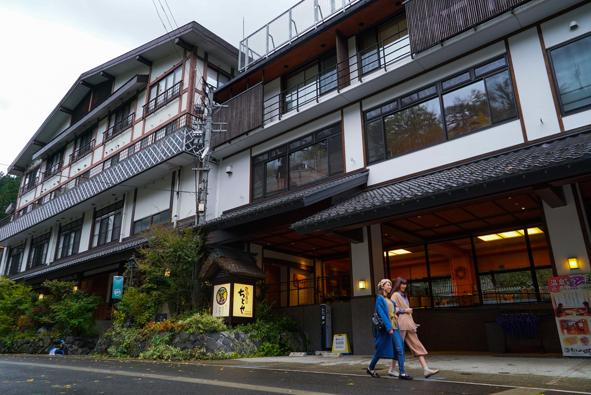 松之山温泉の旅館ちとせ外観と温泉街を歩く人