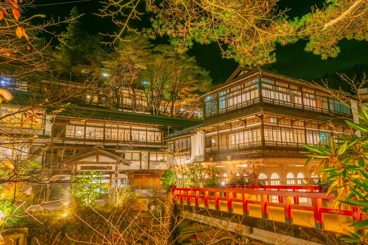夜に明かりが灯る四万温泉の木造旅館と赤い橋