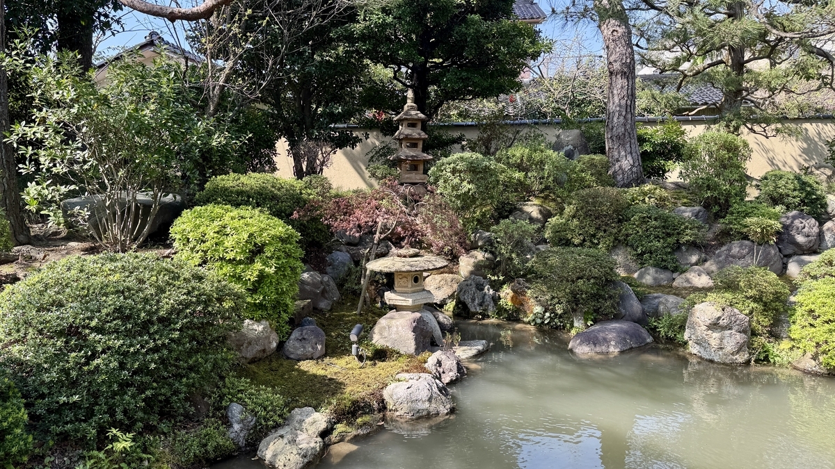 築山の緑と石灯籠が池の周りに配された千田家庭園