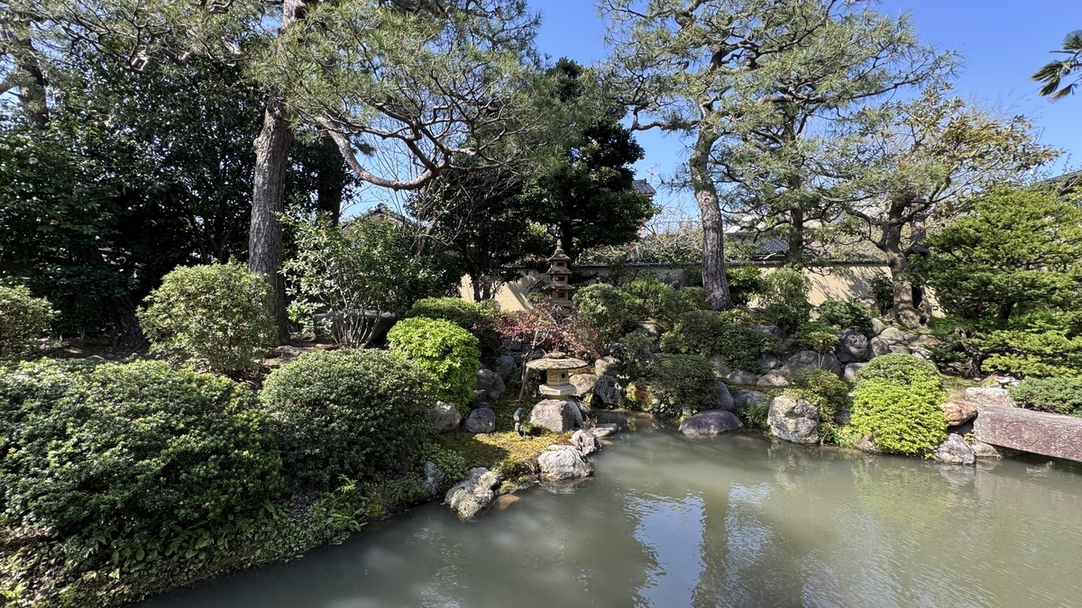 池越しに松や灯籠や石橋を望む千田家庭園の景観