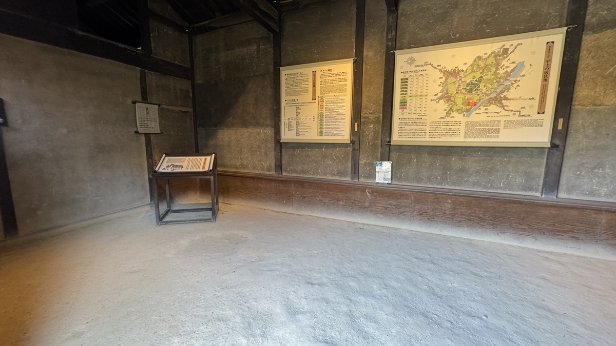 厩内部の土間と壁に掲げられた高田家の展示資料
