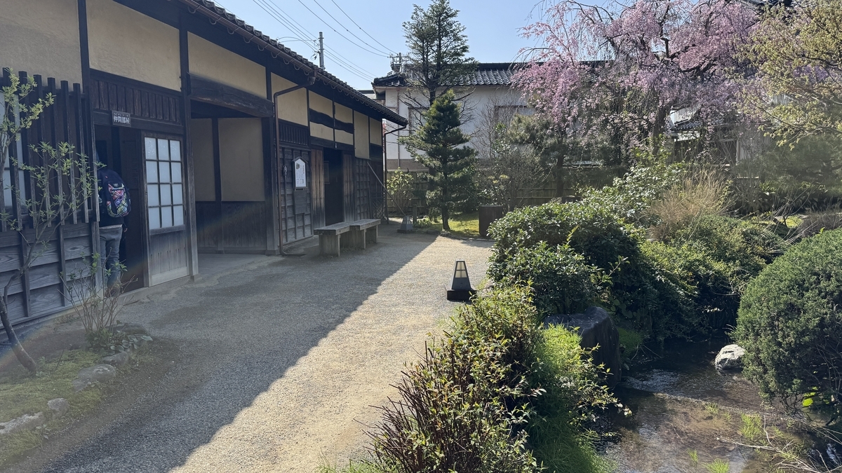 長屋門の建物沿いに続く園路と池泉庭園