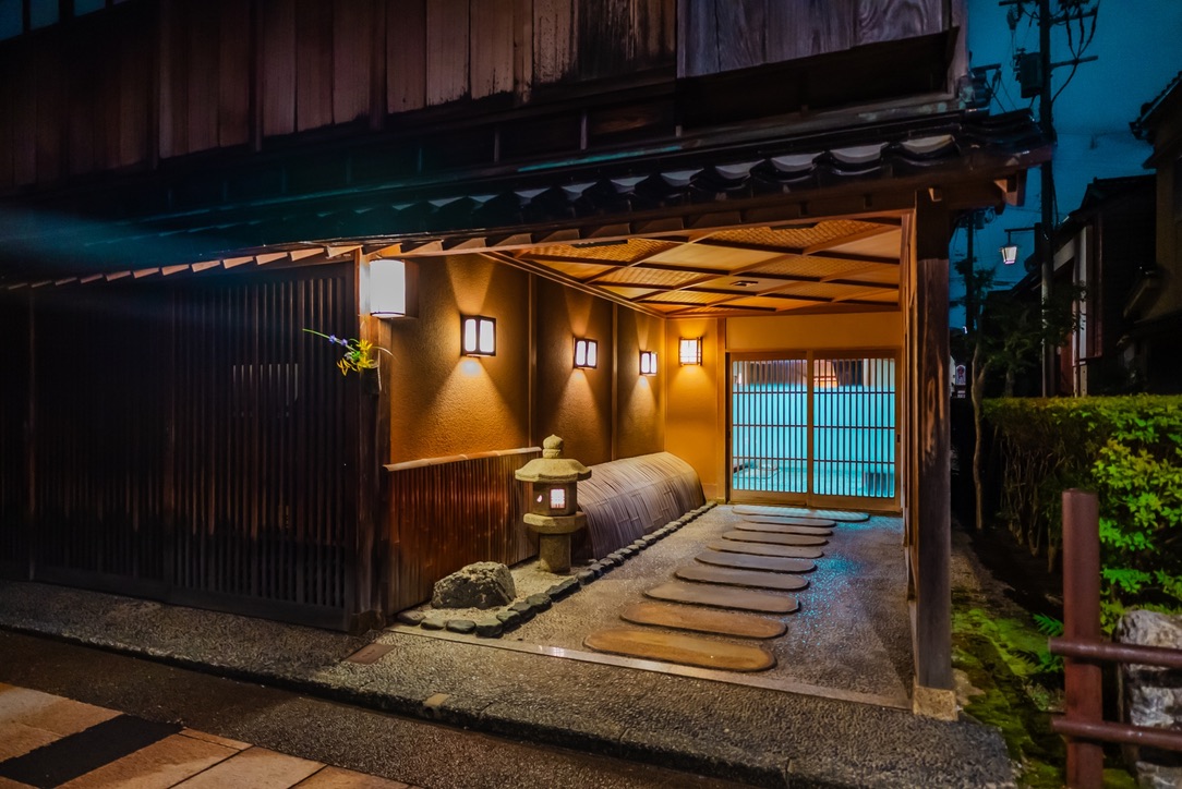 灯りに照らされた茶屋建築の玄関と石灯籠