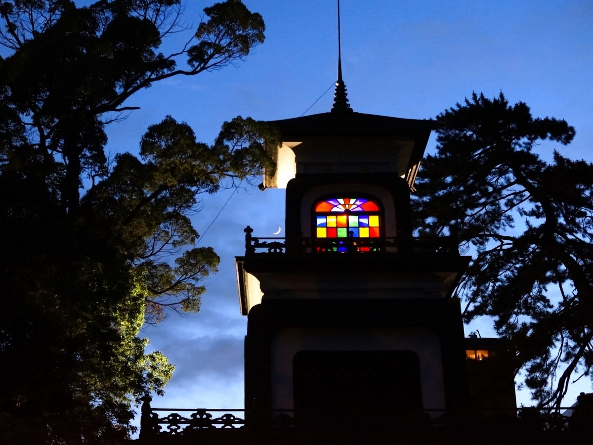 夕闇の尾山神社神門に輝く色ガラスと三日月