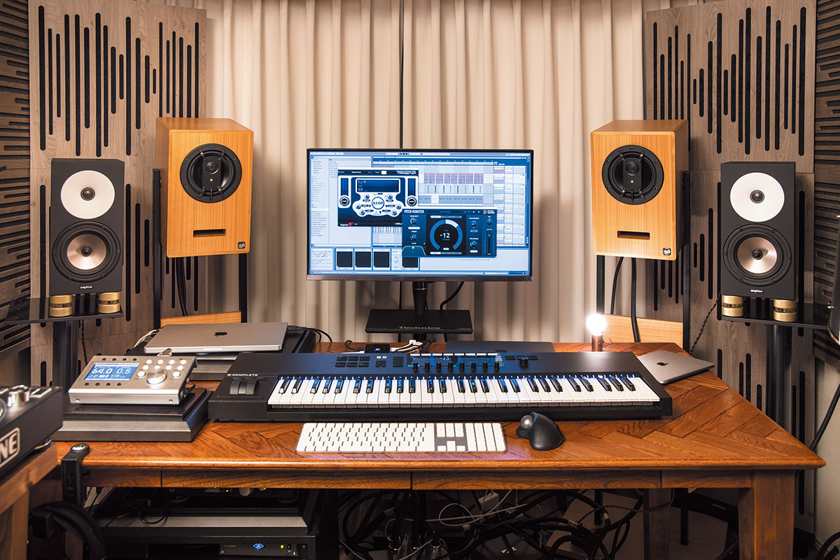 APPLE MacBook ProにABLETON Liveをインストールして使用。モニター・スピーカーはMUSIKELECTRONIC GEITHAIN RL904、AMPHION One18を使い分ける。デスク上にはMIDIキーボードNATIVE INSTRUMENTS Komplete Kontrol  S61、その後方にはOWC Thunderbolt Hub、デスク左にはモニター・コントローラーGRACE DESIGN M905が置かれている。MacBook ProはACOUSTIC REVIVEのクォーツ・アンダーボードRST-38H、M905はTB-38Hを敷いて設置