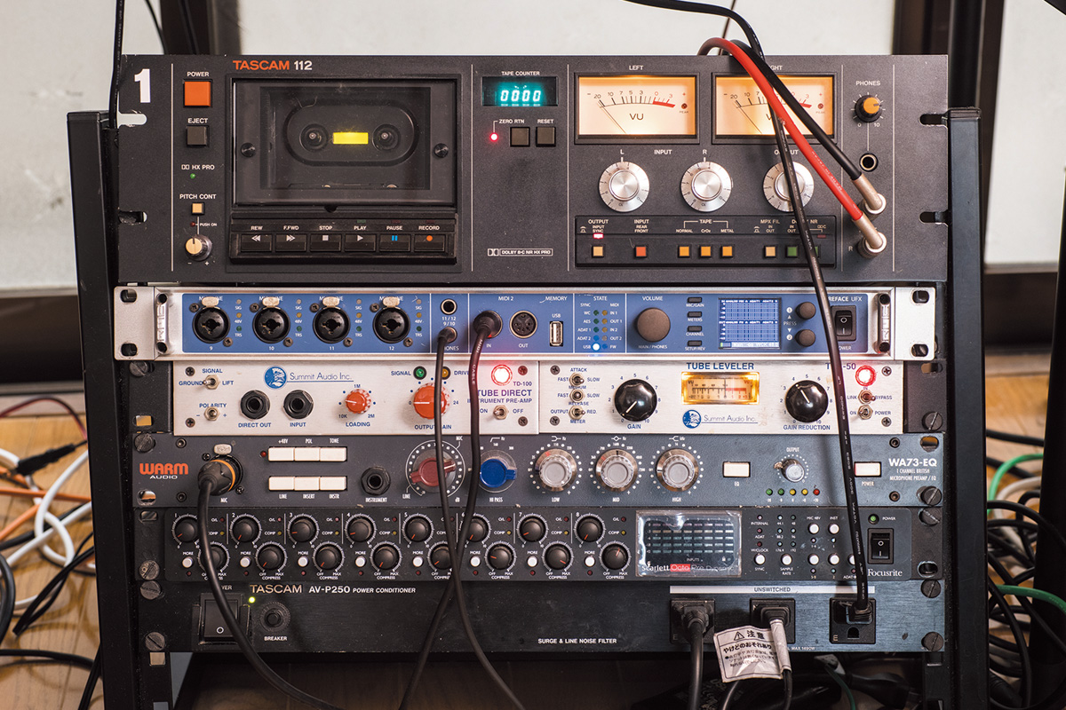 アウトボード・ラック。上から、TASCAM 112（カセット・デッキ）、RME Fireface UFX（オーディオI/O）、SUMMIT AUDIOのTD-100（DI／プリアンプ）とTLA-50（コンプ）、WARM AUDIO WA73-EQ（EQ／マイクプリ）、FOCUSRITE Scarlett OctoPre Dynamic（8chマイクプリ）、TASCAM AV-P250（電源モジュール）。Fireface UFXは活動の初期から使い続けるI/Oで、「ADはすごく大事なんじゃないかなと考えていて、買って正解でした。モニターの音もすごくクリアです」と語る。112はライブ音源をカセットとして販売するためのもの