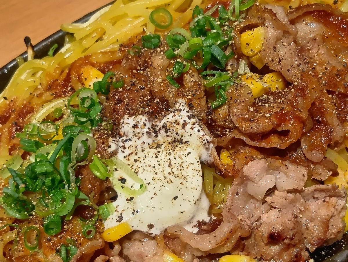 熱々の鉄板に乗ったやよい軒『牛バターちゃんぽん焼』のクローズアップ。牛肉、ちゃんぽん麺、バター、コーン、ネギ、黒胡椒が見える。