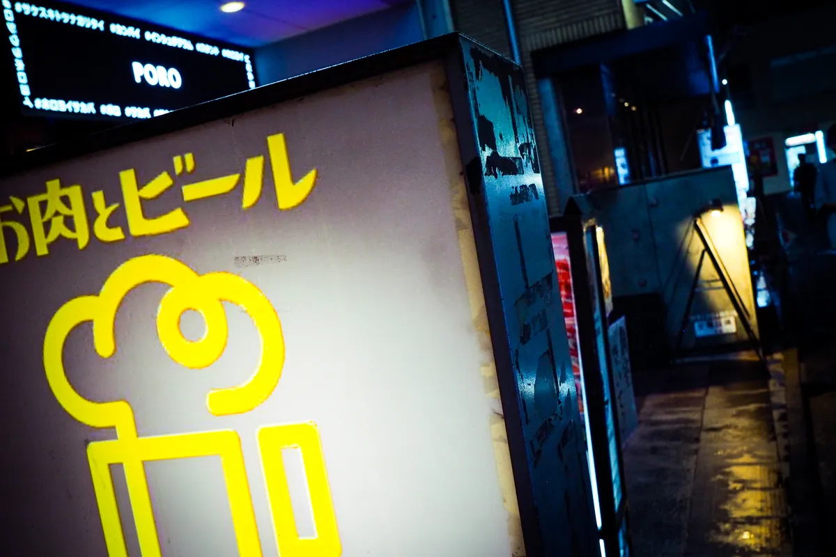 夜の街角のネオンと濡れた路面の反射