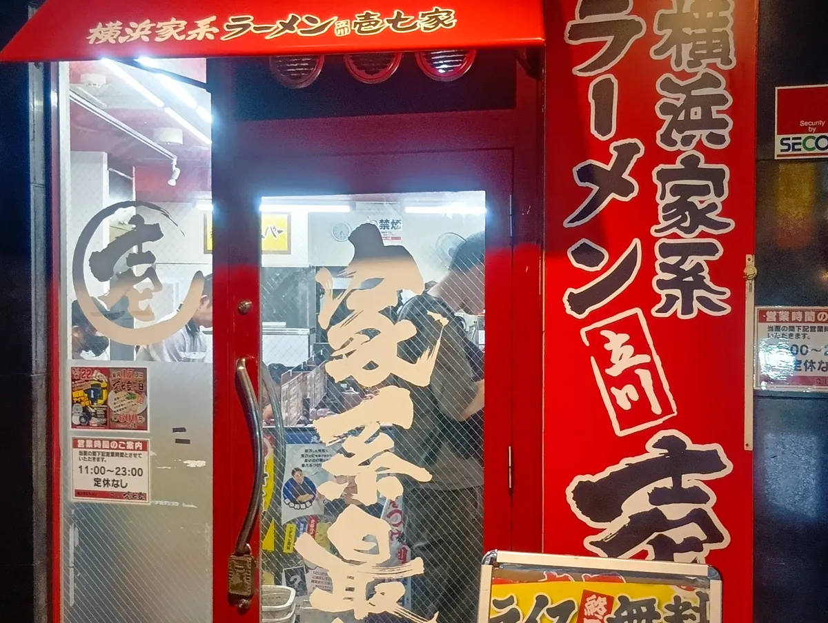 横浜家系 ラーメン壱七家の赤い入口ドア。営業時間「11:00～23:00 定休日なし」の表示。