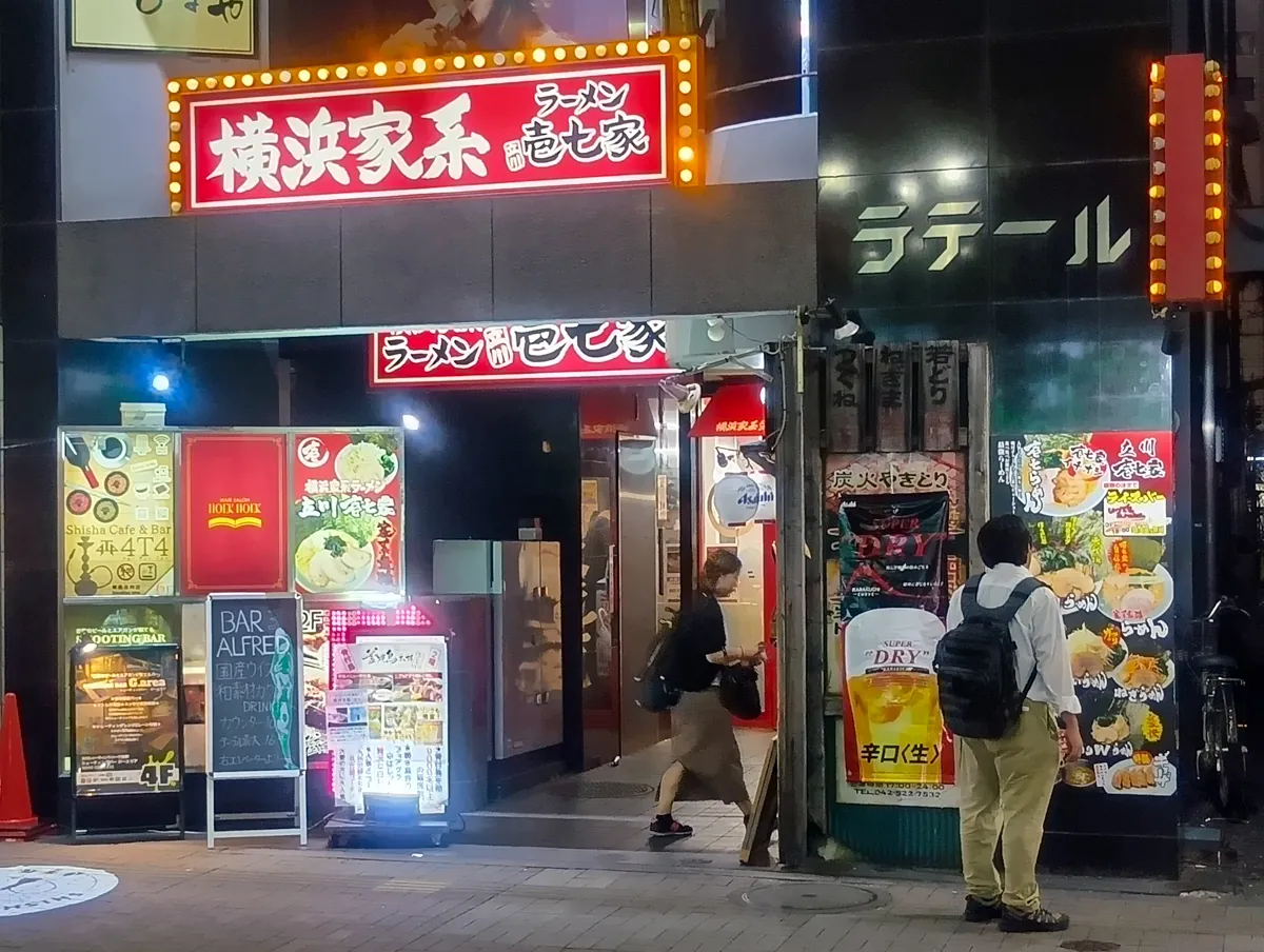 横浜家系 ラーメン壱七家の夜の外観。赤と白の看板が目立つ。