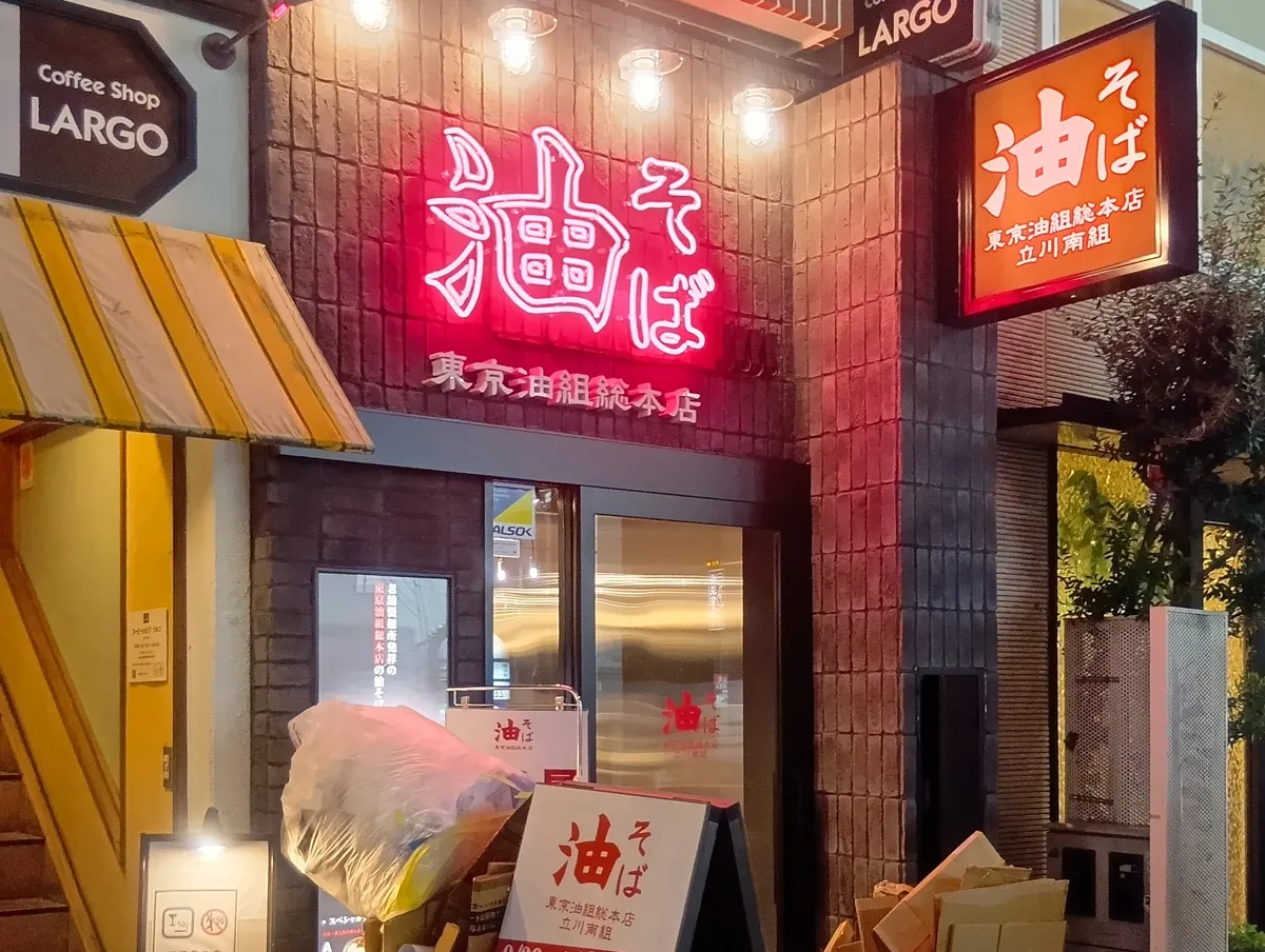 油そば 東京油組総本店 立川南組の夜の外観。赤いネオンサインが目立つ。