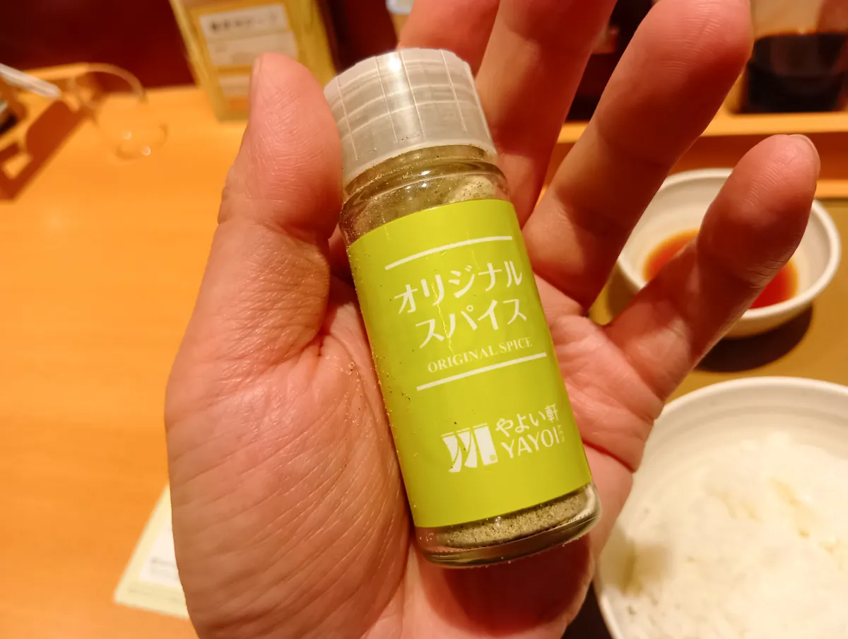 やよい軒のオリジナルスパイスボトルを手に持っている様子