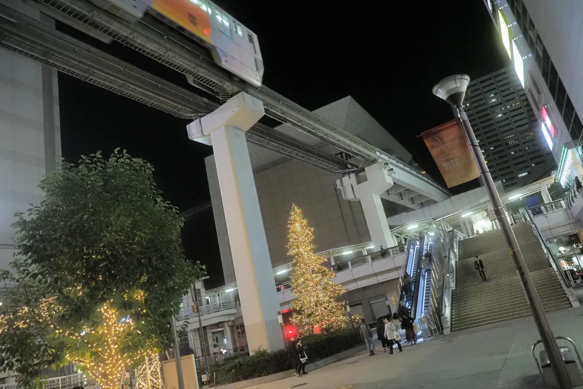 夜空の下、立川のモノレールがクリスマスツリーの上を通過する様子。