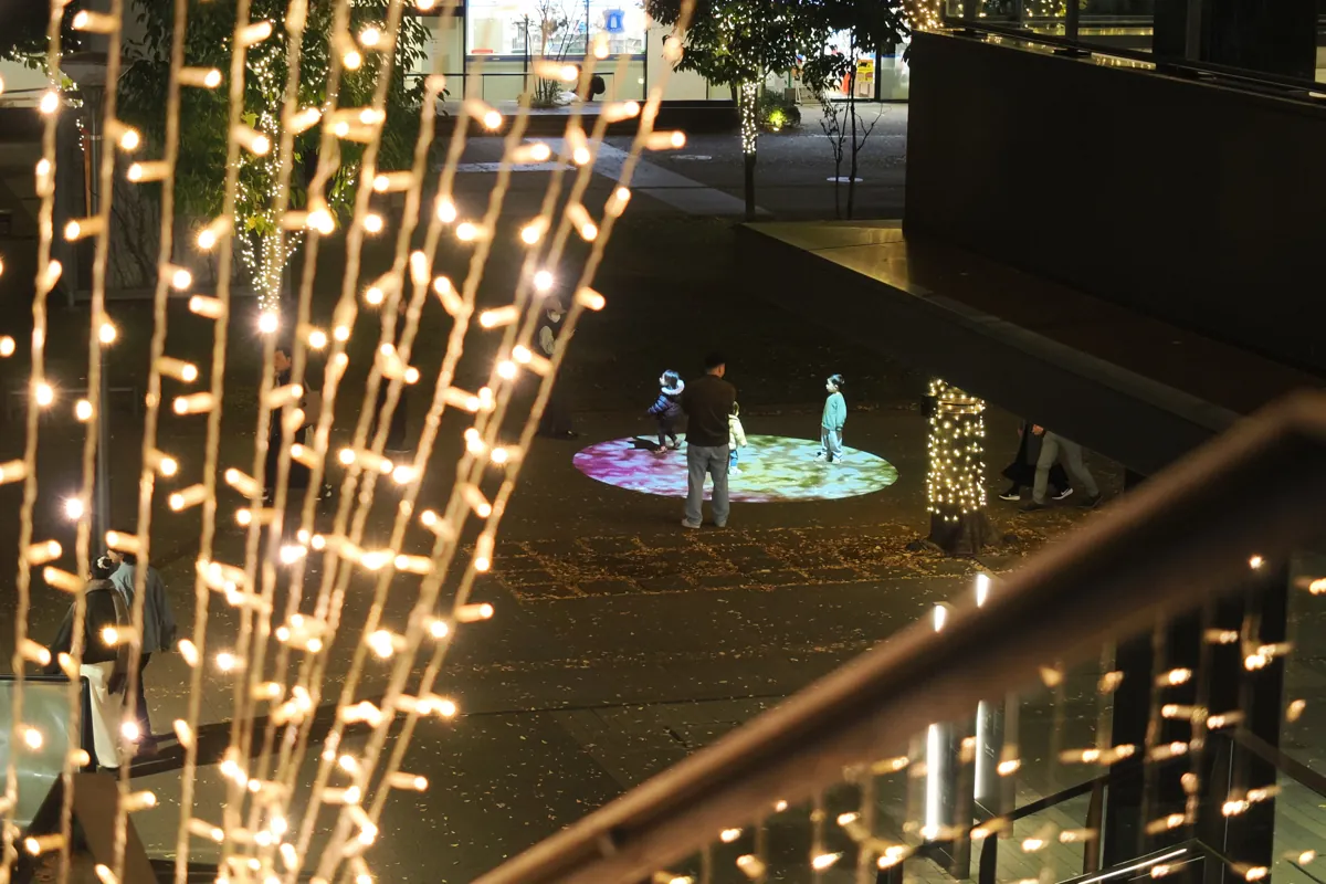 イルミネーションの地面に投影された光の上で遊ぶ子供たち。
