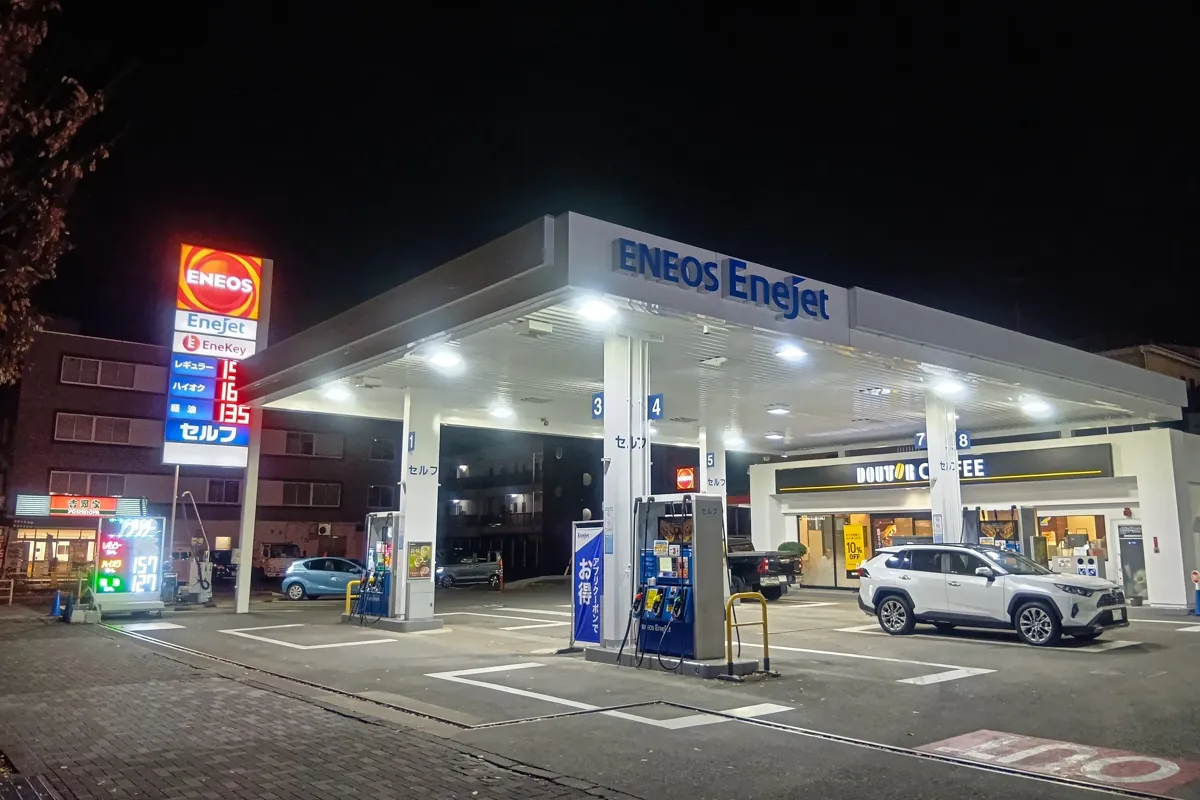 夜間のガソリンスタンドENEOS EneJetの正面からの写真。明るく照らされた給油所と価格表示板が見える。