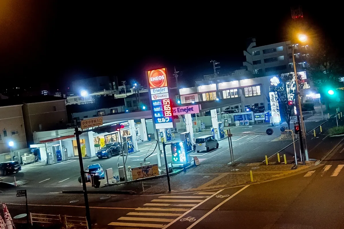 夜間のガソリンスタンドENEOS EneJetを俯瞰で撮影した写真。道路や信号も写り、日常の給油風景を示す。