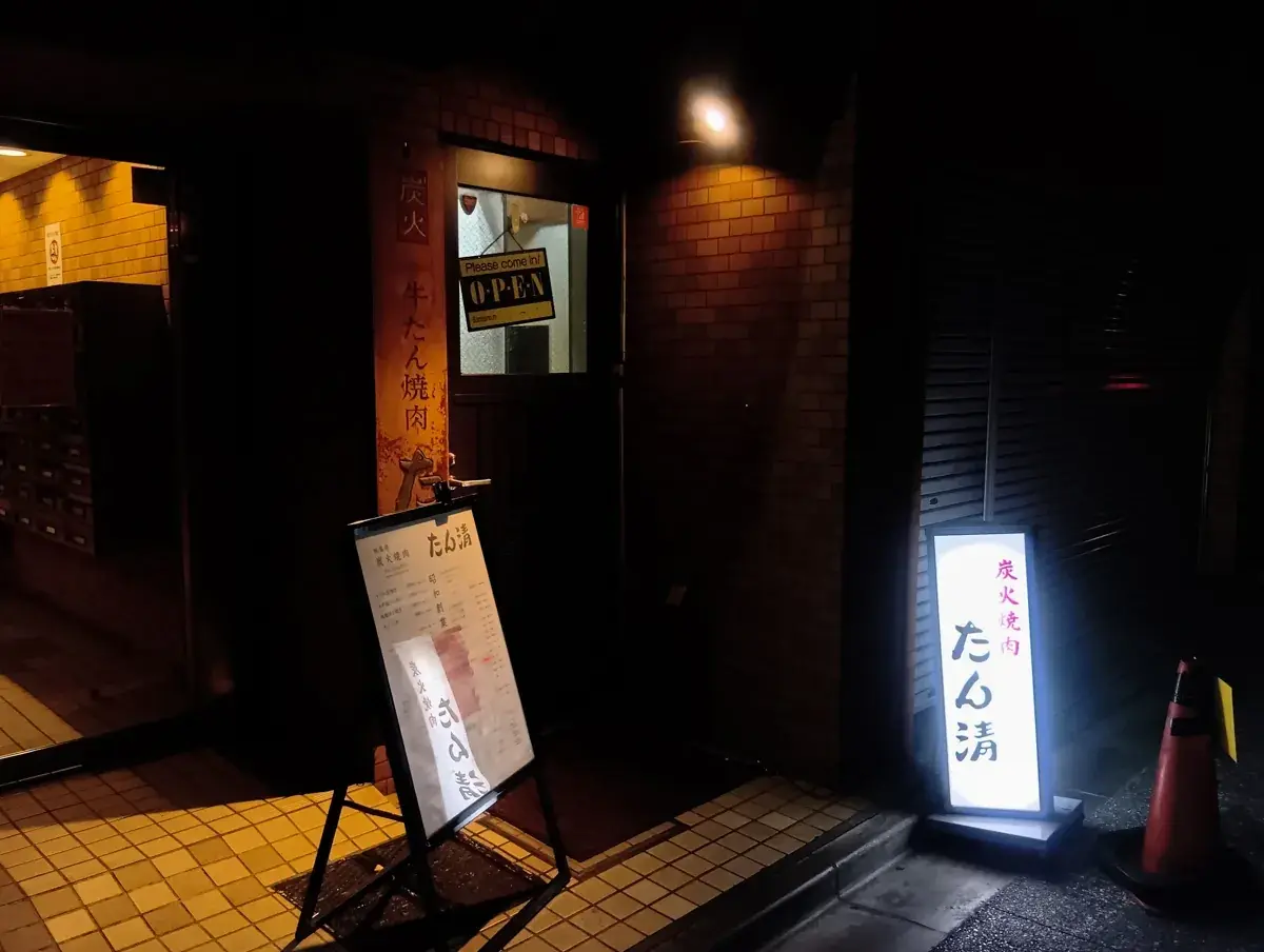 秋葉原の焼肉店「たん清」本店の外観。夜の街に光る看板と入り口のカラーコーン
