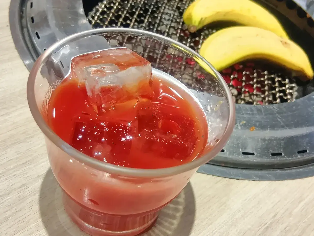 グラスに注がれた真っ赤なトマト酒。氷が浮いており、非常に濃厚そうな色合い