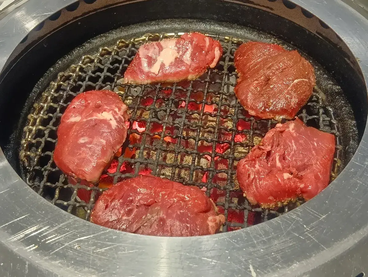 網の上で焼かれる上ロース。炭火の熱で脂が浮き出し、美味しそうな焼き色がついている