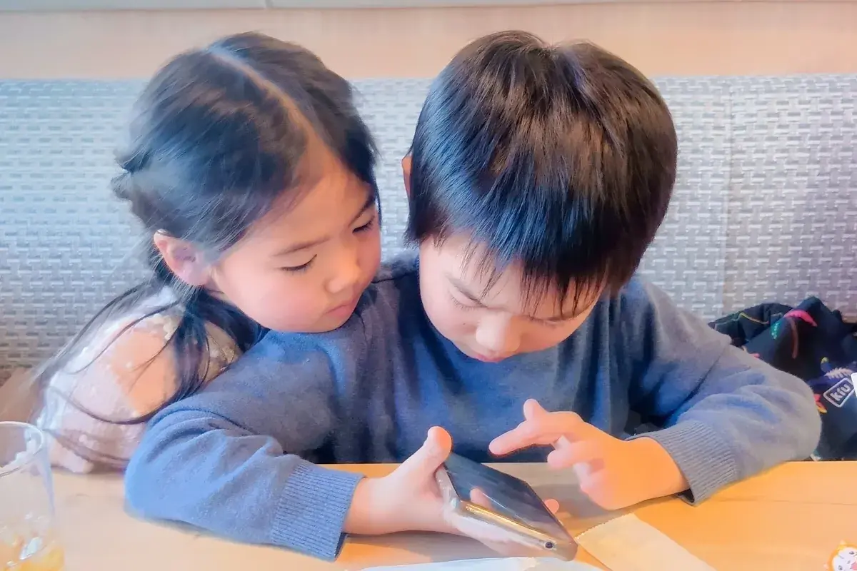 仲良くスマホを覗き込む二人の子ども
