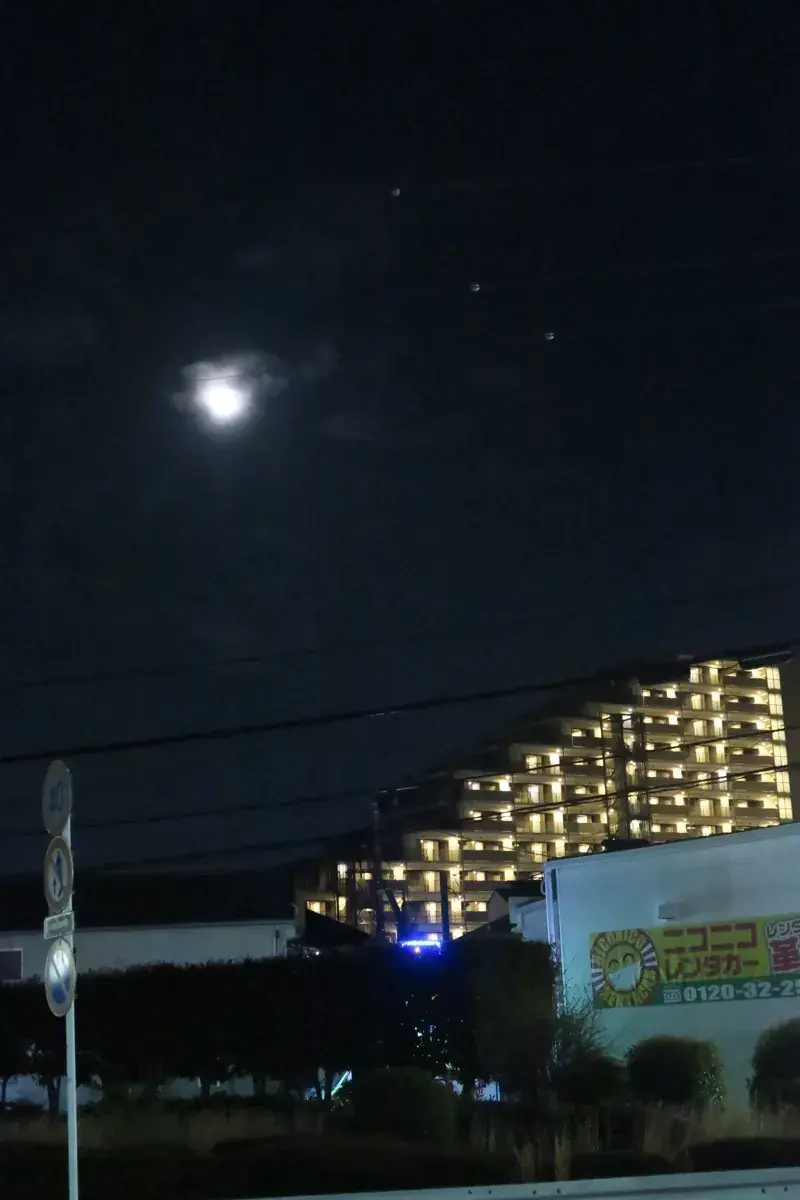 夜空に浮かぶ、街灯を反射して白く光る電線の留め具。暗い空に3つの白い点が並んでいる。