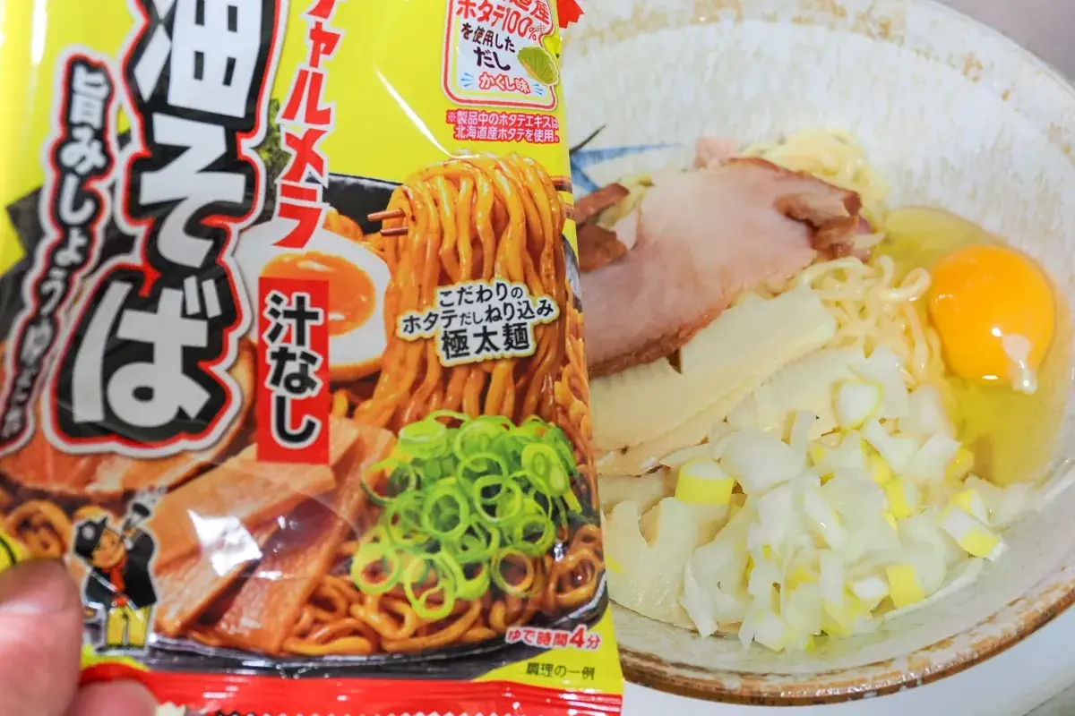 インスタントの袋麺「チャルメラ 汁なし油そば」のパッケージと、その盛り付け例に極限まで寄せて具材（卵、ネギ、チャーシュー、そして薄切りのたけのこ）を配置した一皿。