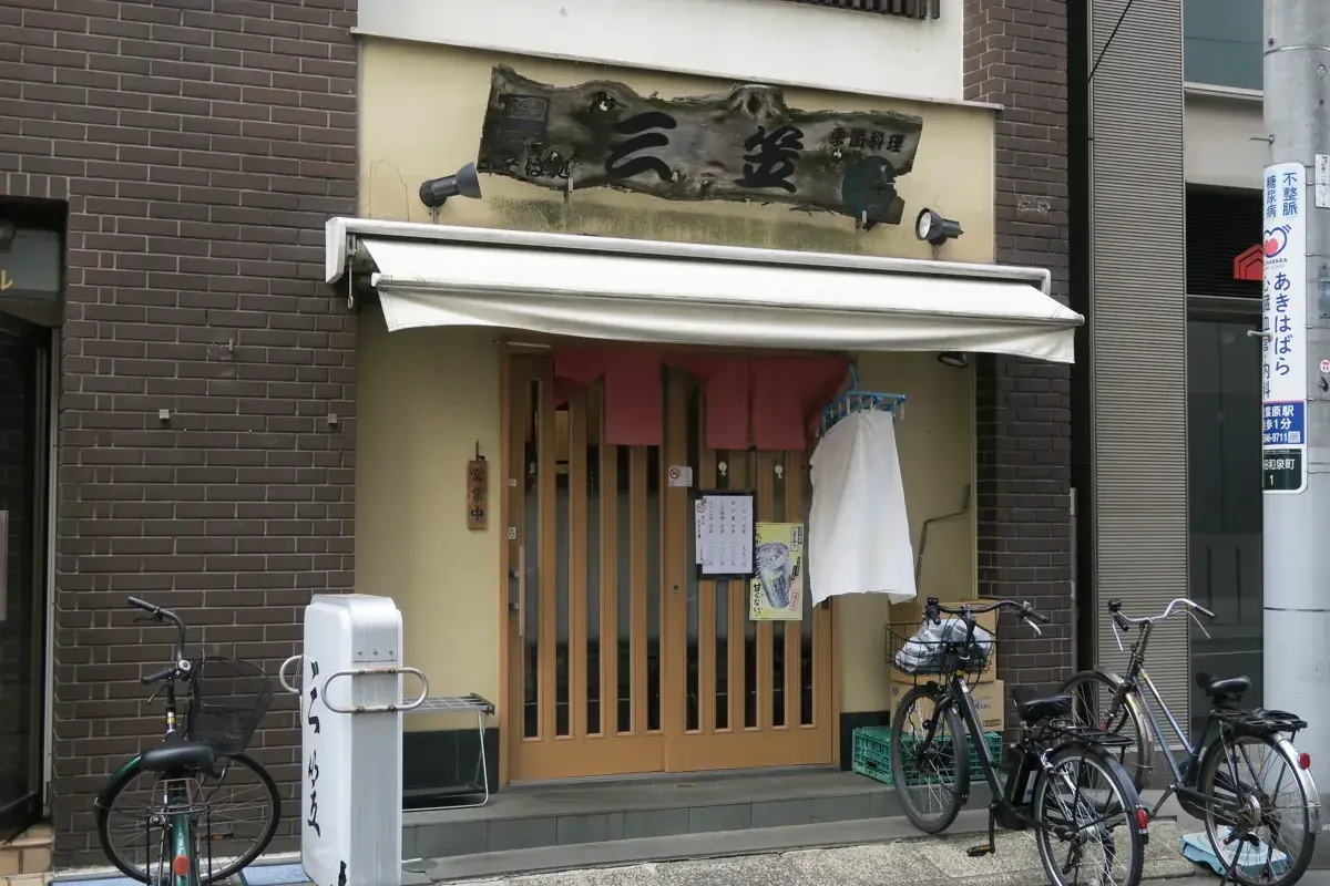 秋葉原の路地裏にある飲食店「三笠」の外観。年季の入った木の看板と、店先に並ぶ自転車。