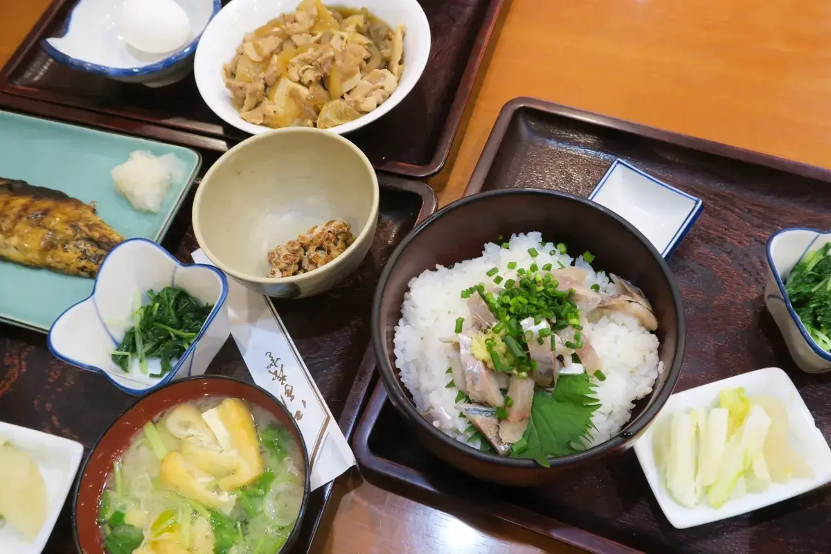 三笠のテーブルに並ぶ、アジたたき丼、肉豆腐、さば塩焼きの3つの定食。