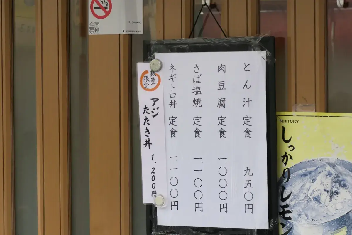 三笠の入り口に貼られたお品書き。とん汁、肉豆腐、さば塩焼などの定食メニューと、数量限定「アジたたき丼 1,200円」の貼り紙。