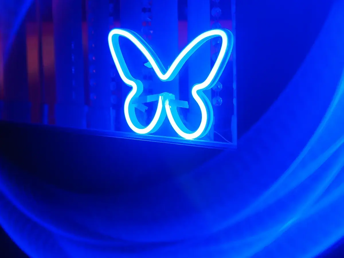 青い蝶のネオンサインにNeewer Hole Effectフィルターをかけた夜景作例。渦巻きボケになりリング状の虹色を放っている。