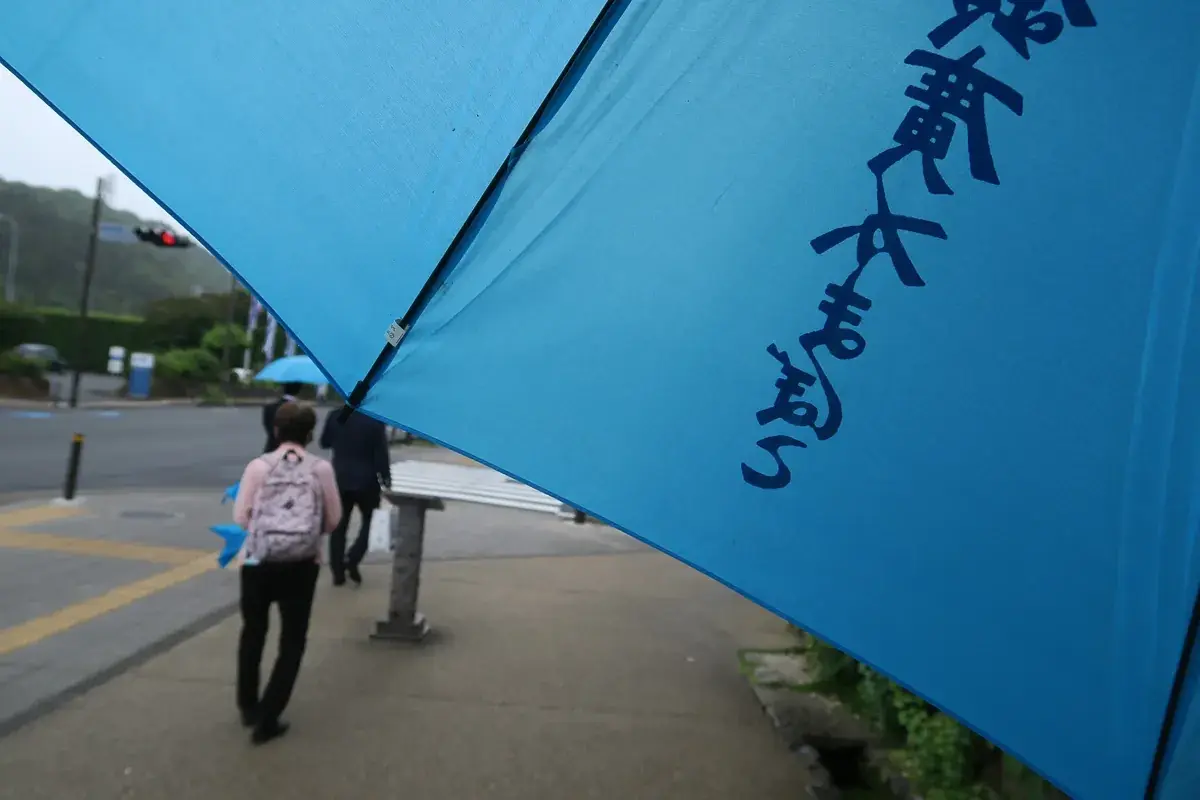 土産屋の前に立つ青い傘。雨粒が傘を伝い、濡れた歩道に箱根の静けさが広がる。
