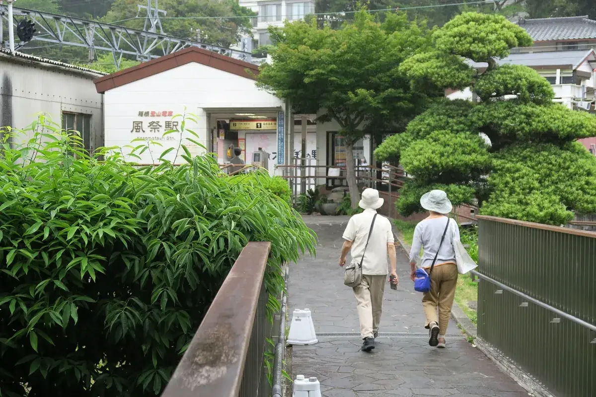 雨上がりの道を駅へ向かって歩く後ろ姿。