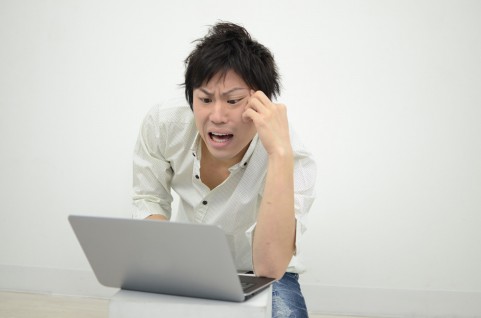 PCを見て悩んでいる男の写真