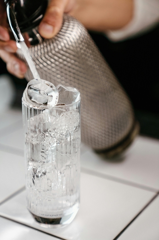 氷入りのグラスへ炭酸水を注ぐ、ハイボール作りのイメージ