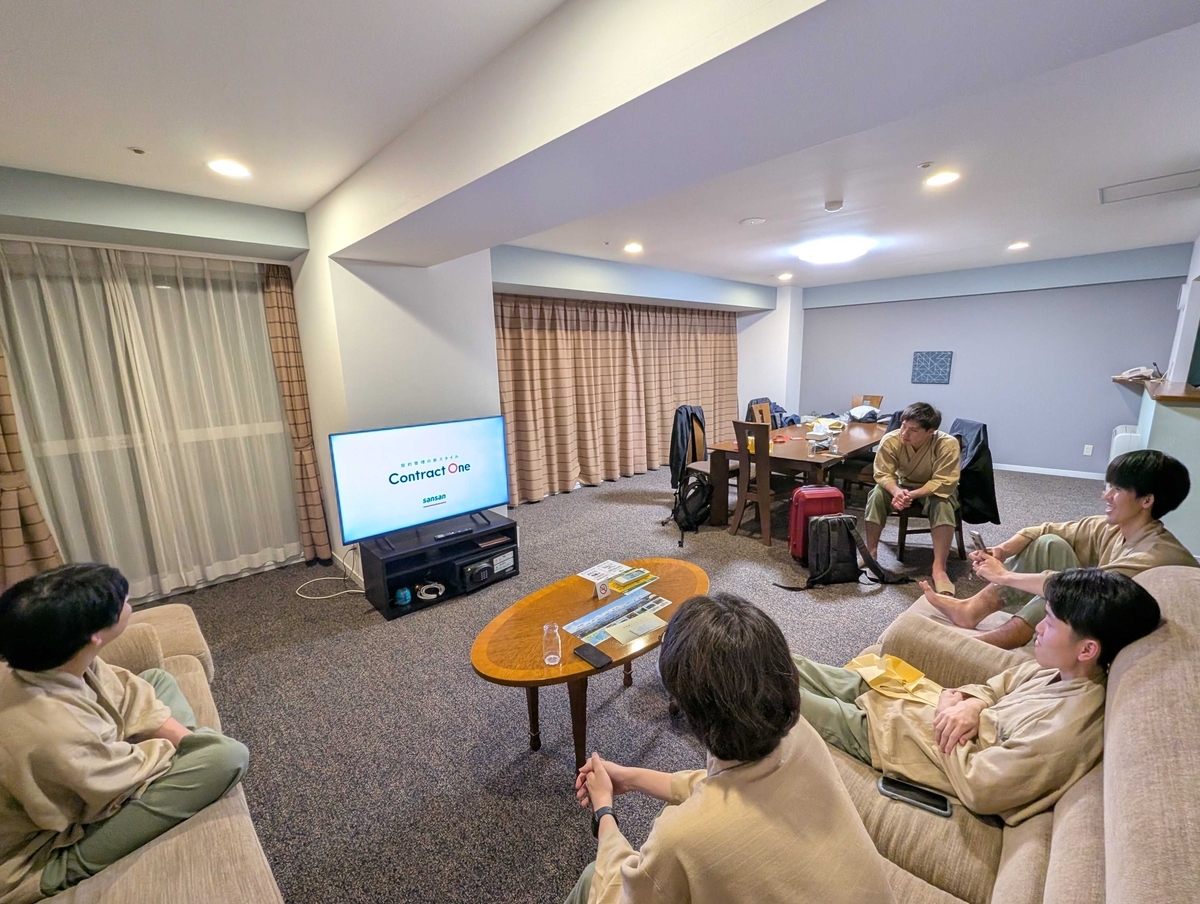 部屋に集まってテレビを囲み、ContractOneのCMを鑑賞している