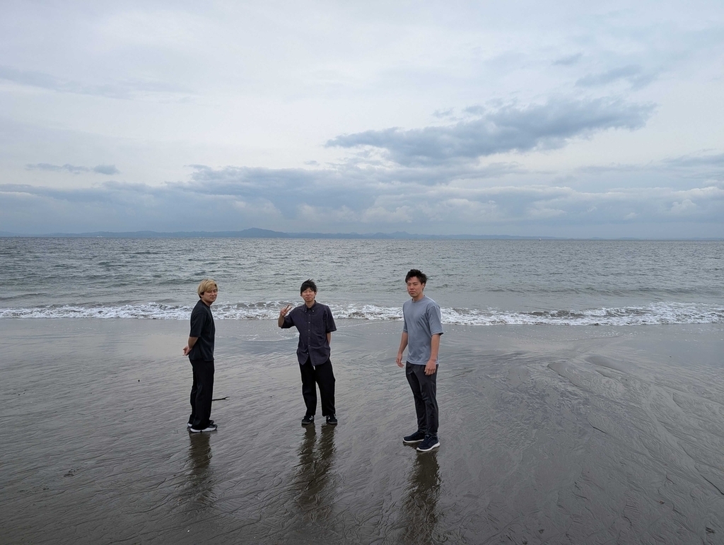 海まで散歩し、参加したエンジニア３人が海の前で記念撮影している