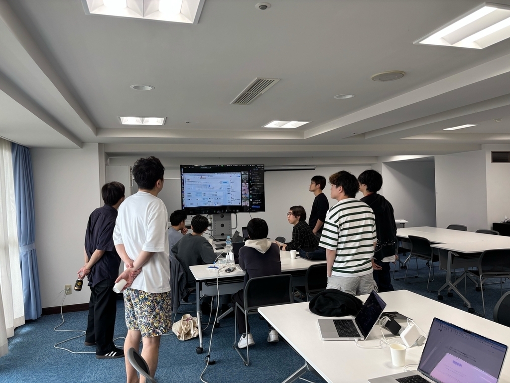 大きなディスプレイをみんなで囲み、オンラインミーティングに参加している様子