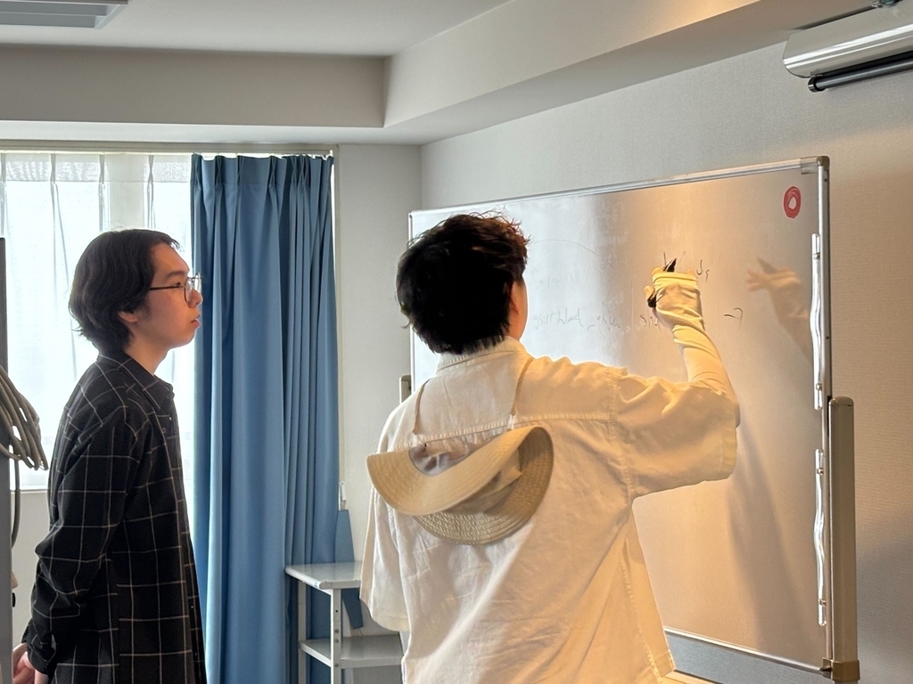 ホワイトボードの前で2人のエンジニアが相談している様子