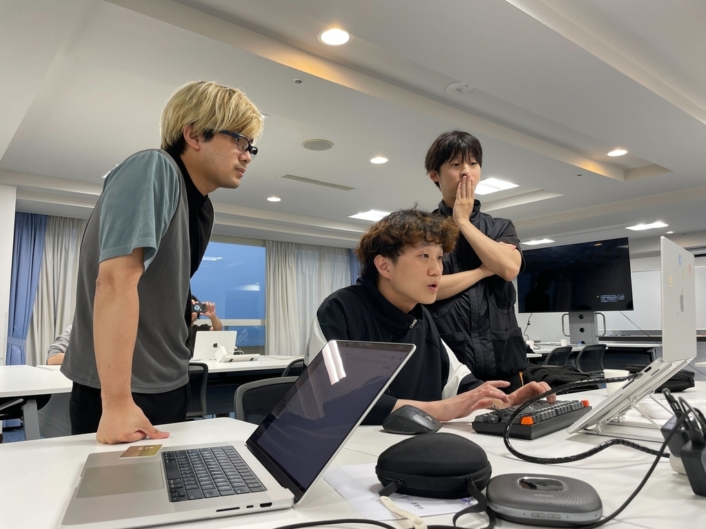 １つのパソコンをチームメンバーが囲んでリリース作業をしている様子