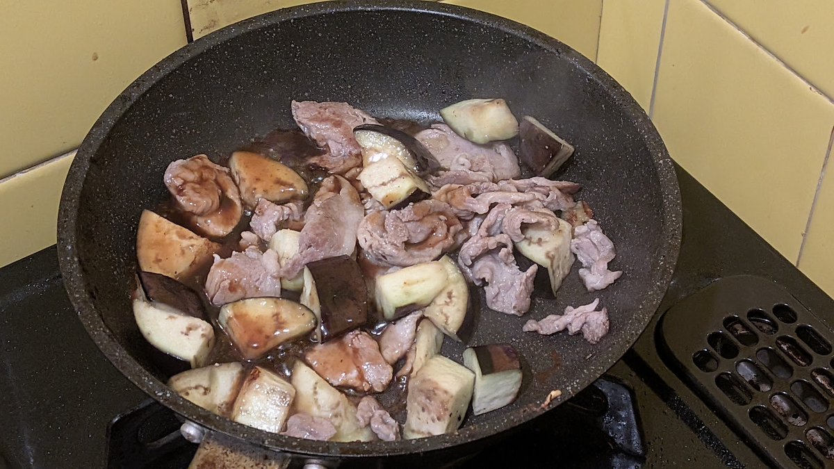 フライパンでお肉とナスが炒められている