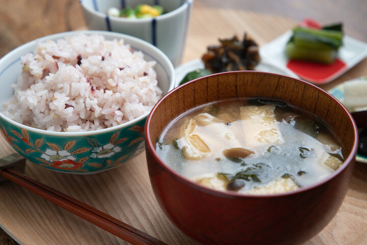 朝日が差し込む食卓に並ぶ、湯気のたつ味噌汁と白ごはんの和食の朝食