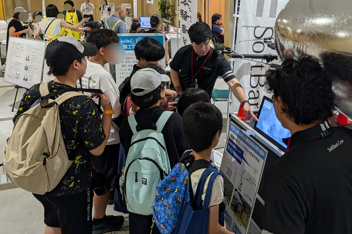 会場では、子どもたちが「HAPS」の模型と一緒に記念撮影をしたり、実際にドローンのコントローラーに触る姿も。また、映像を見ながら社員の説明を真剣に聞く親子も多数見られました。