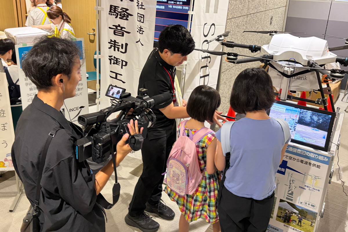 会場では、子どもたちが「HAPS」の模型と一緒に記念撮影をしたり、実際にドローンのコントローラーに触る姿も。また、映像を見ながら社員の説明を真剣に聞く親子も多数見られました。