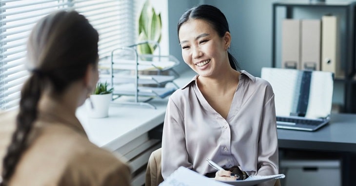 にこやかに会話をしながら同僚といい関係を築いているビジネスパーソン
