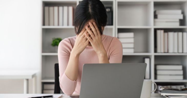 仕事をするにあたり自信が持てず、デスクに肘をついて顔を手で覆う女性