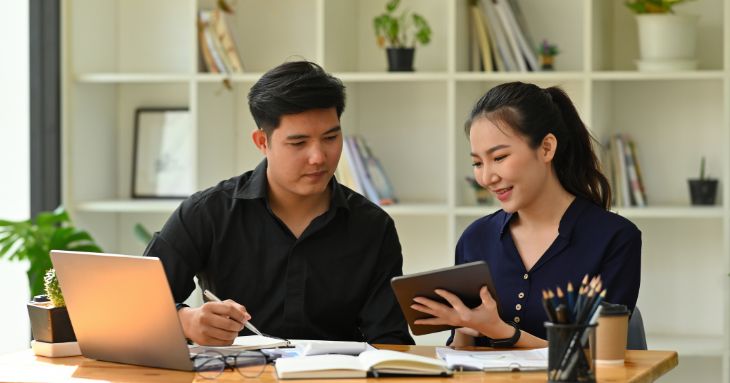男性と女性が並んで座り、女性がタブレットを手に男性に説明をしている